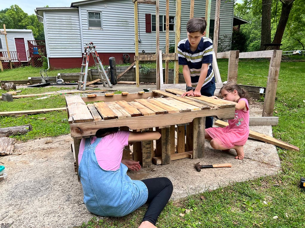 siblings making a mud kitchen out of pallets