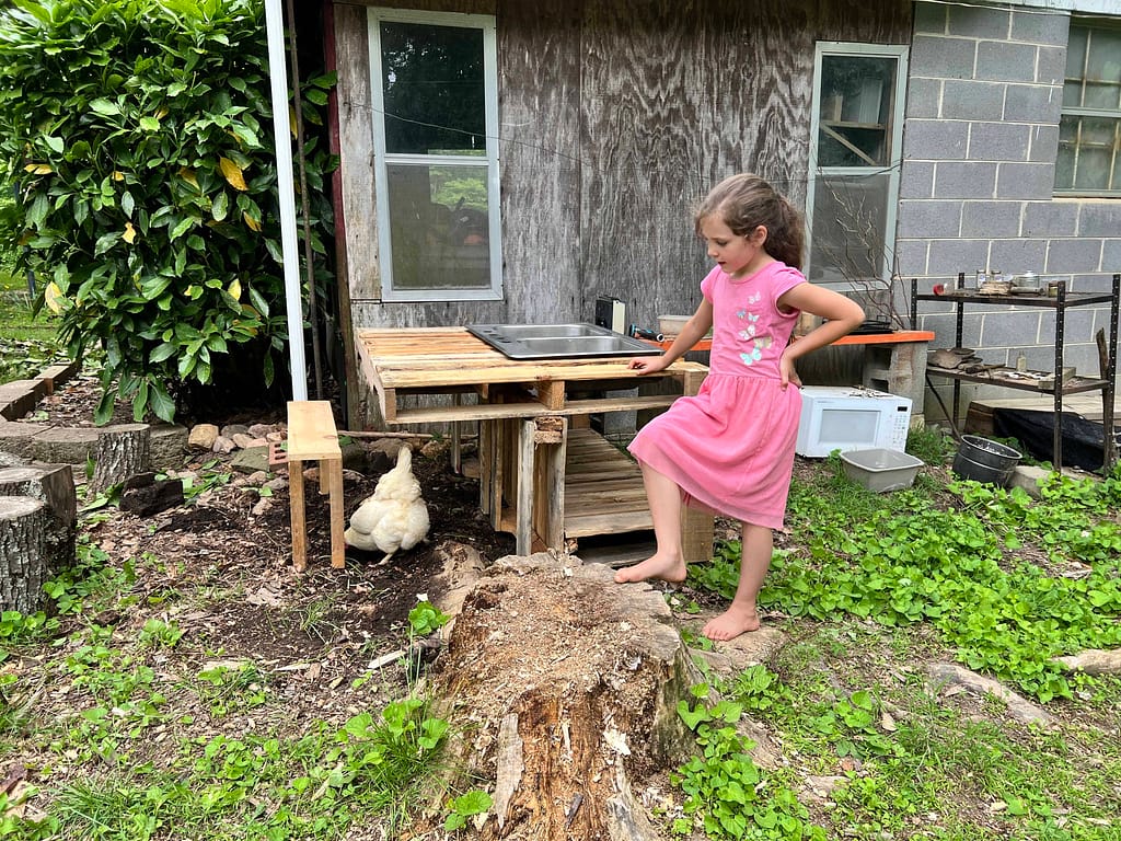 7 year old standing next to her mud kitchen