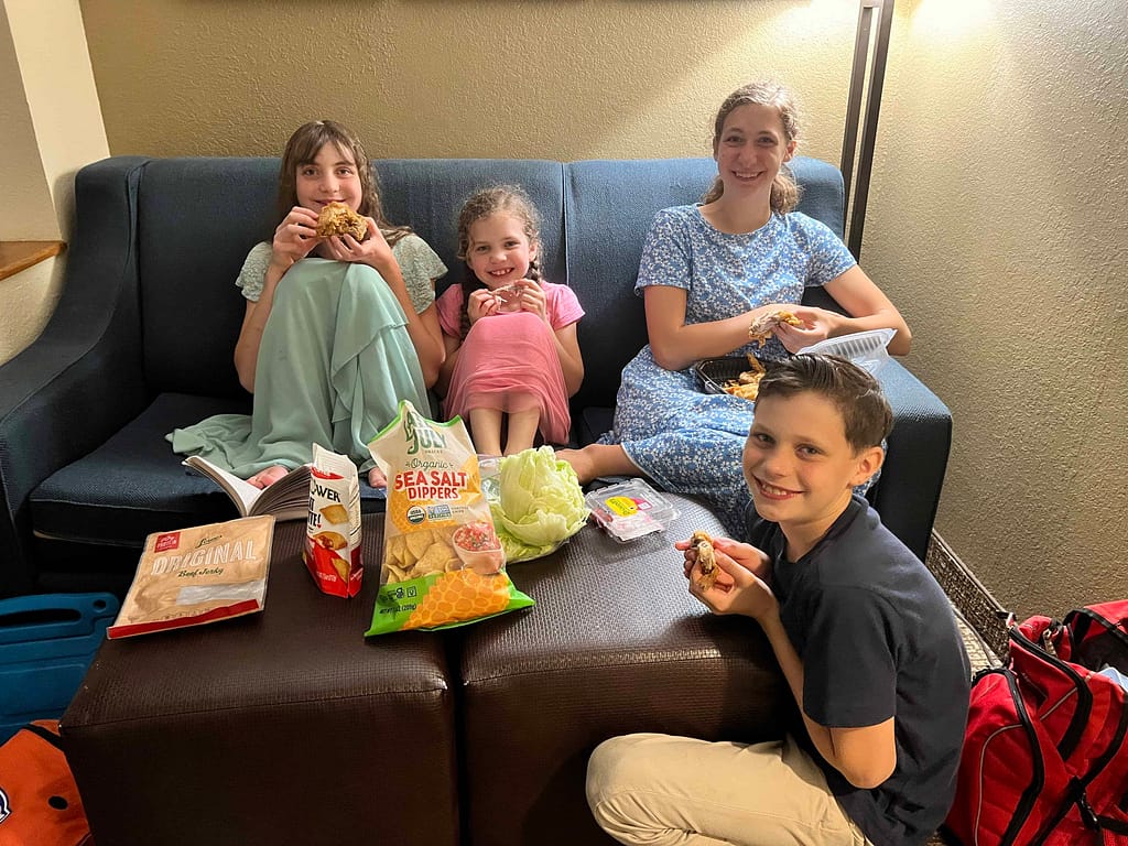 4 siblings eating dinner on a couch at a hotel