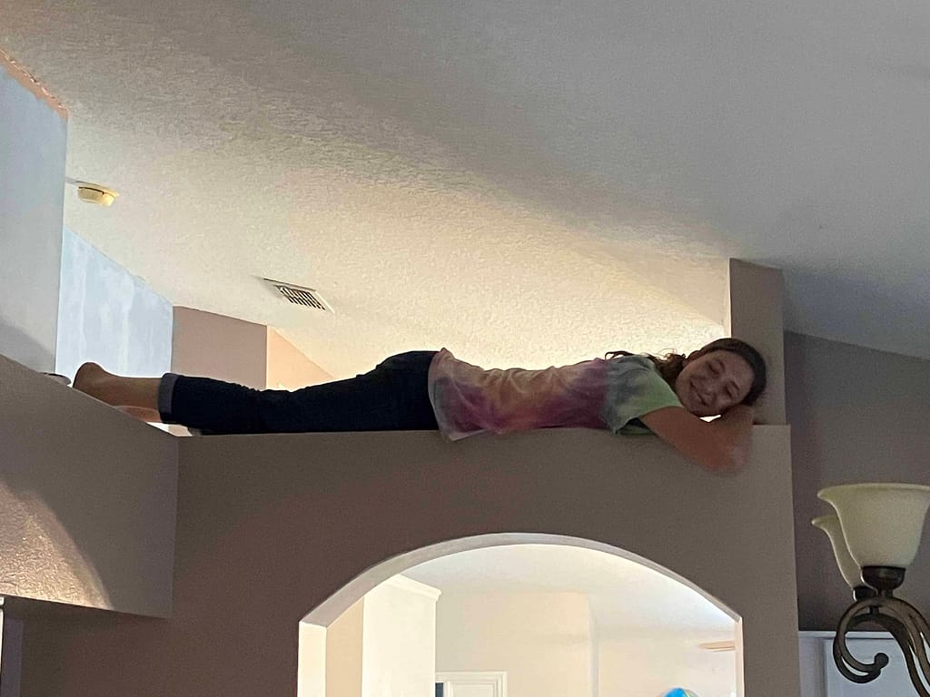 15 year old girl resting on a ledge in a vaulted ceiling room