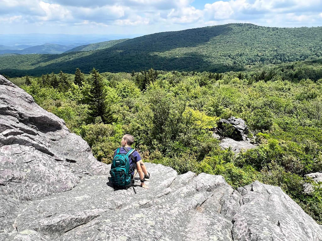 11 year old boy on a massive rock looking at the mountains below