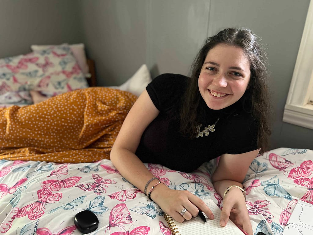23 year old woman writing in journal on bed