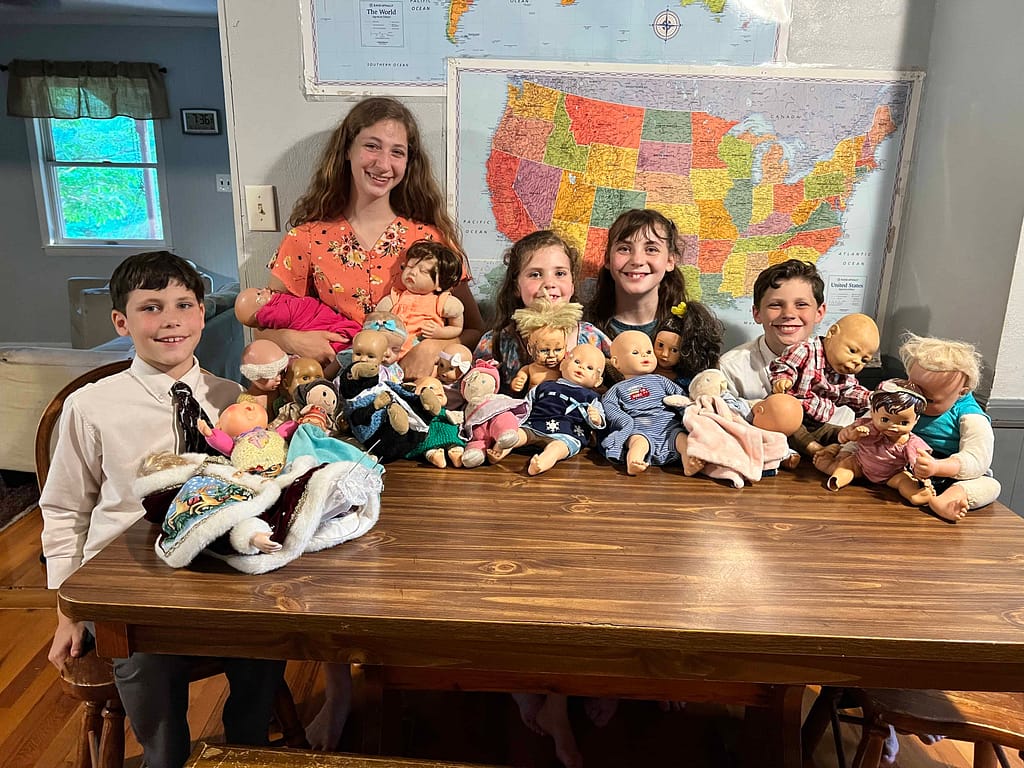 5 kids posing with lots of dolls