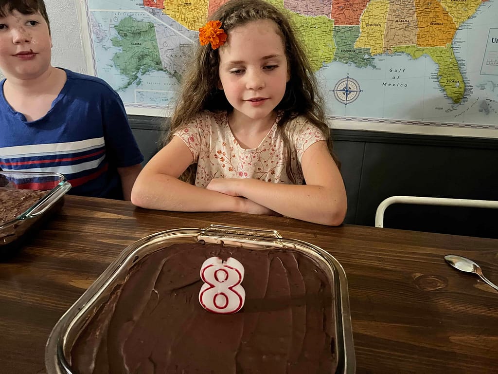 girl turning 8 and blowing out a candle