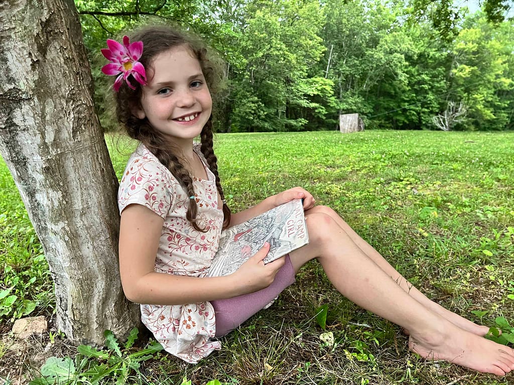 7 year old reading under a tree