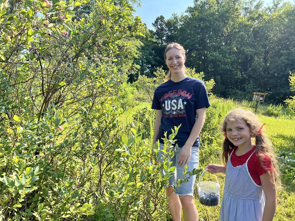two sisters picking blueberries