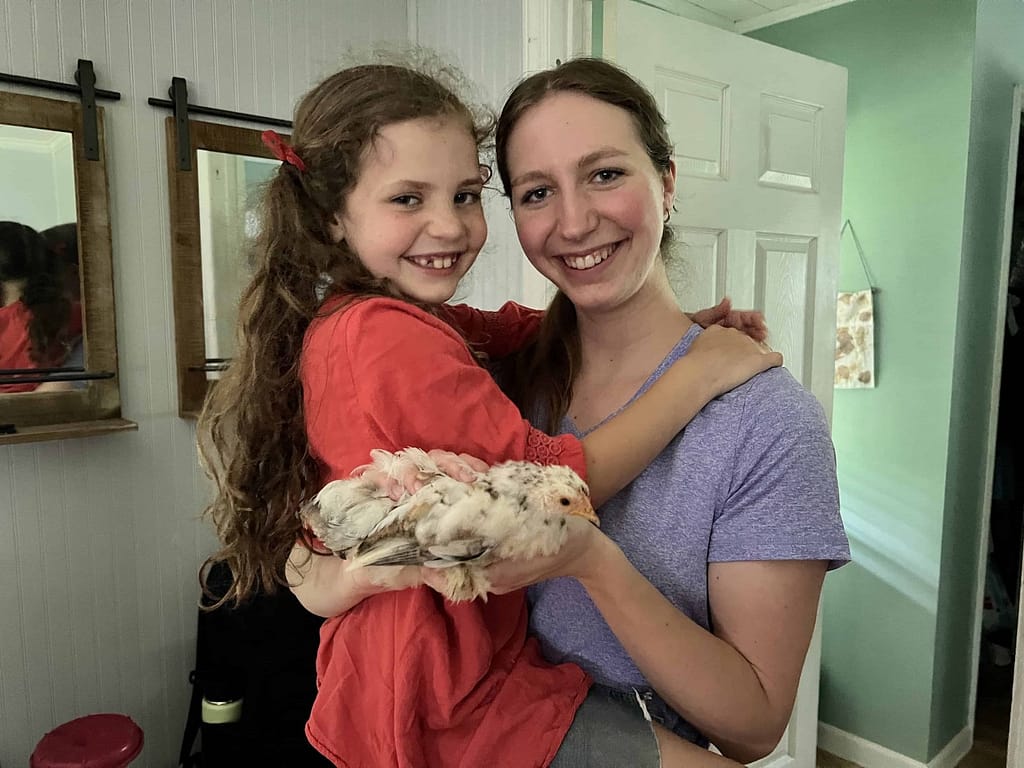 sister holding younger sister and chick