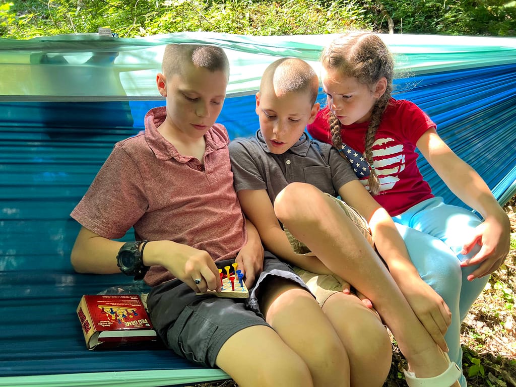 three kids playing a game in a hammock