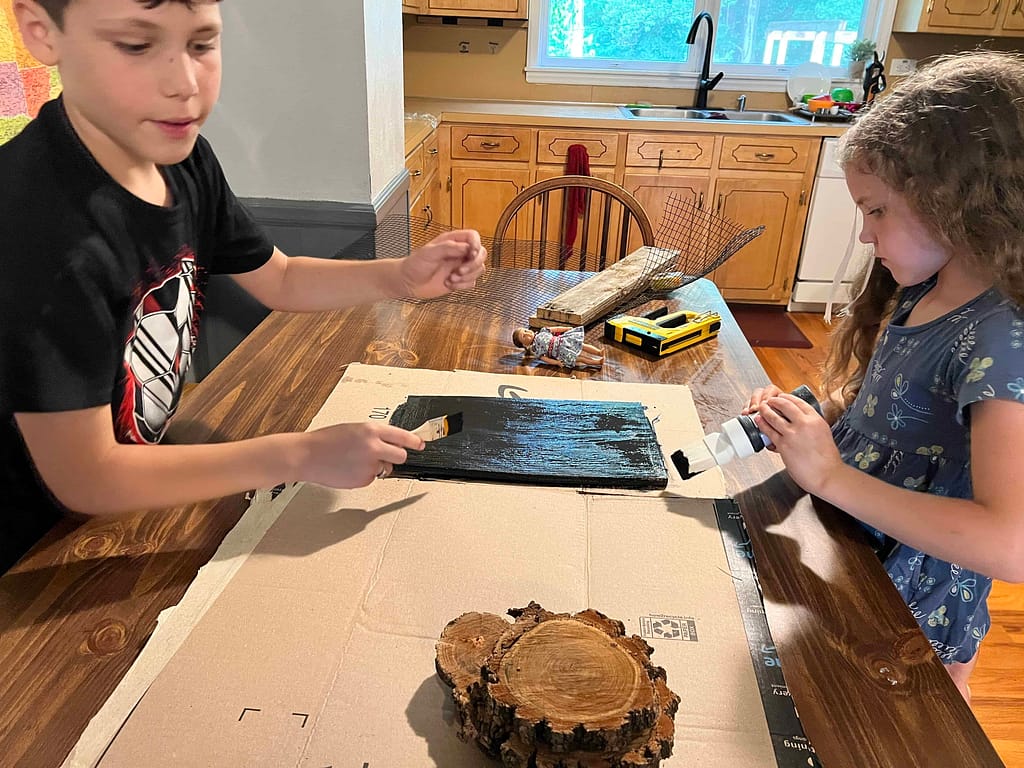 two kids painting wooden stove burners and griddle
