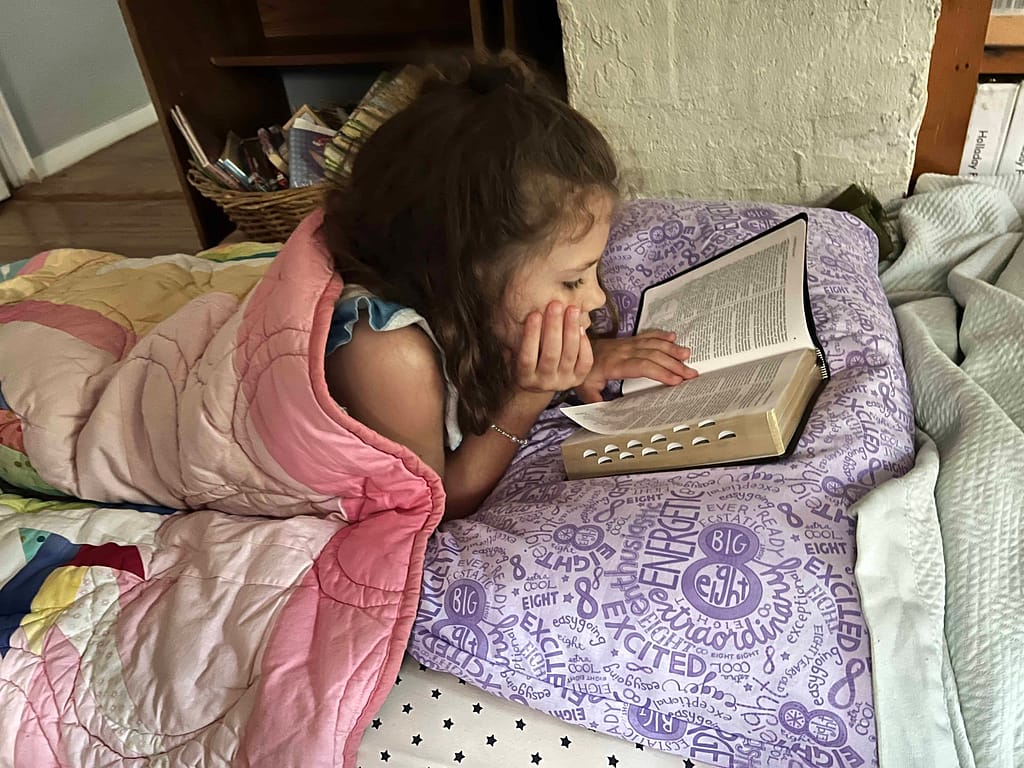 8 year old girl reading scriptures in bed