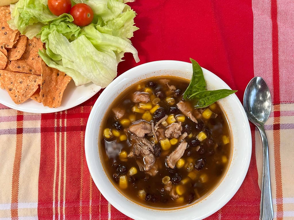 bowl of enchilada soup with side salad and chips