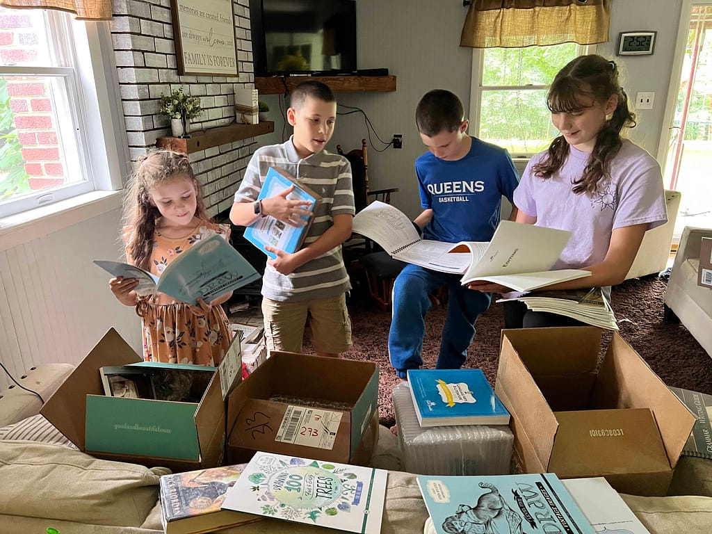 4 kids looking at school books that came in the mail