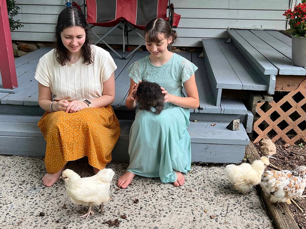 2 sisters holding chickens on the porch