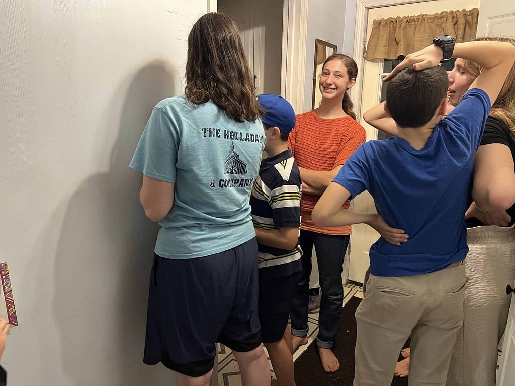 siblings measuring and marking heights on the wall