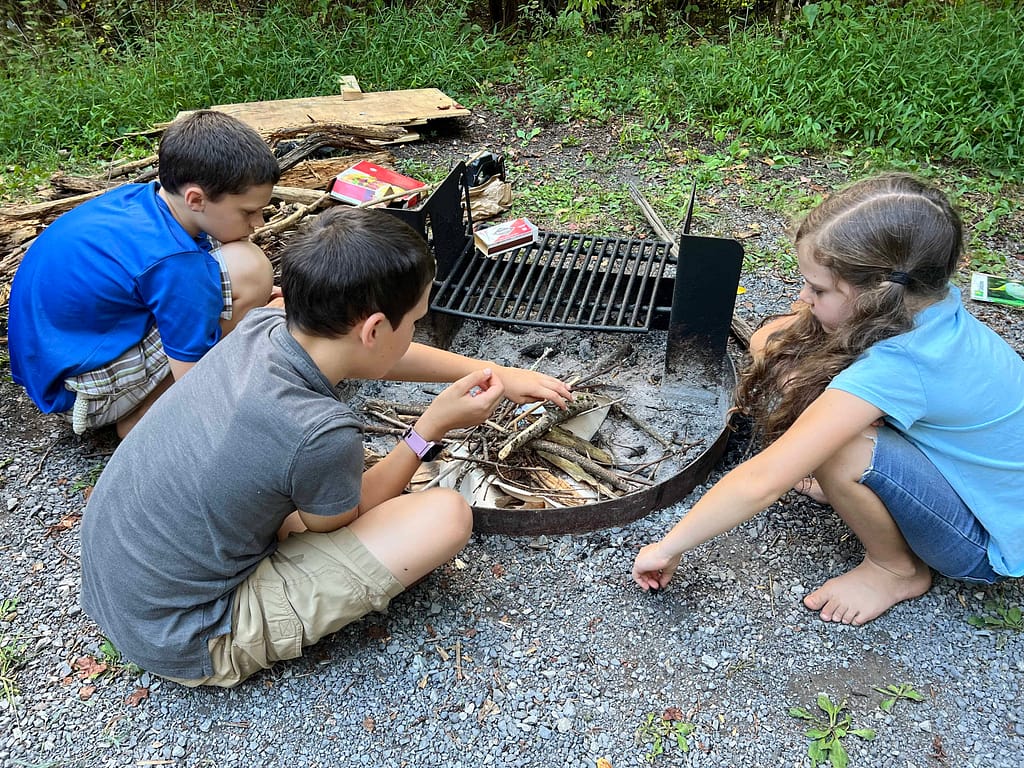 3 kids starting a fire at a campground