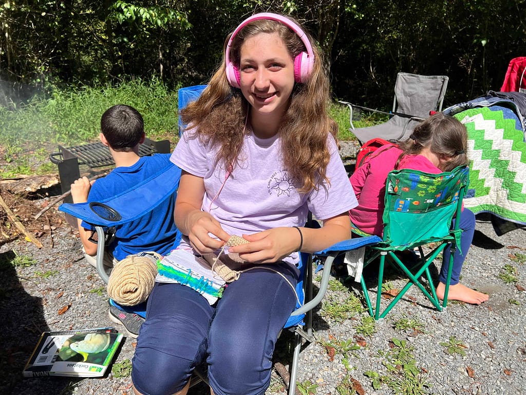 girl listening to audio book while camping