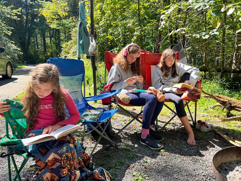 3 girls reading while camping