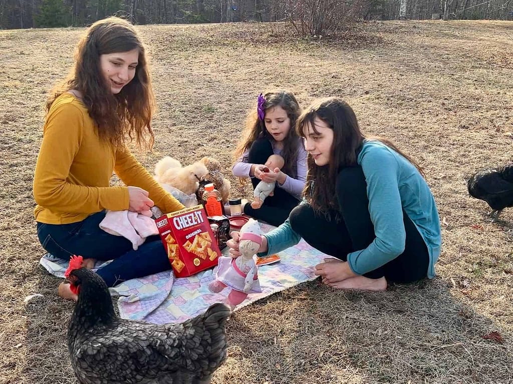 3 sisters having picnic with dolls