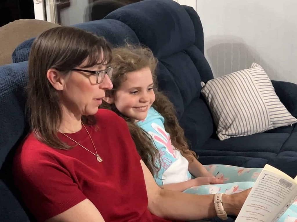 mom reading chapter book to young girl