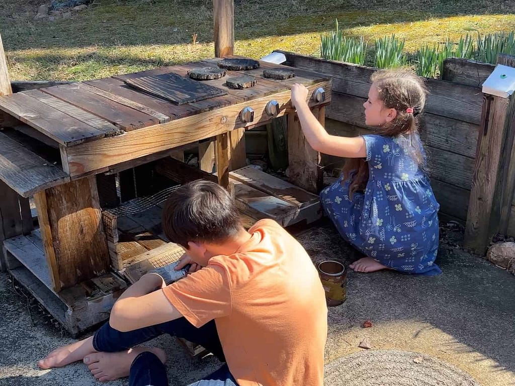 two kids stain a mud kitchen
