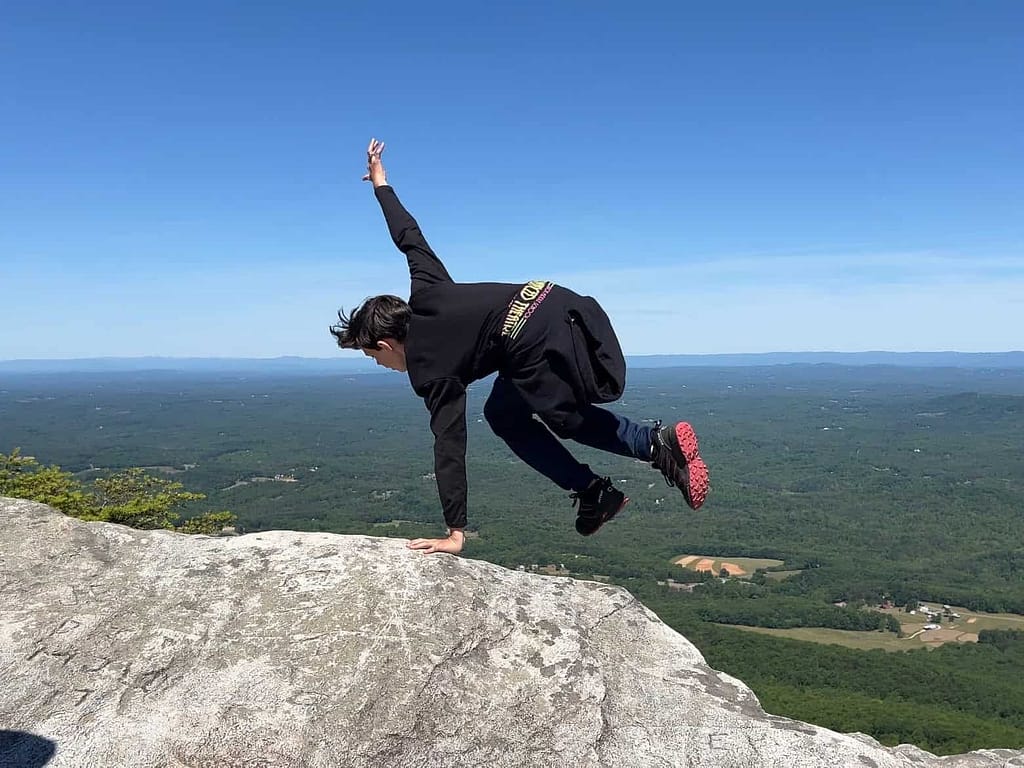 boy pretending to jump off a rock cliff