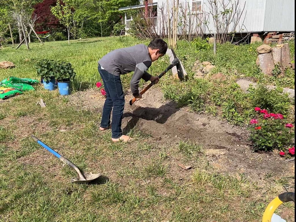 boy uses pickax to dig hole