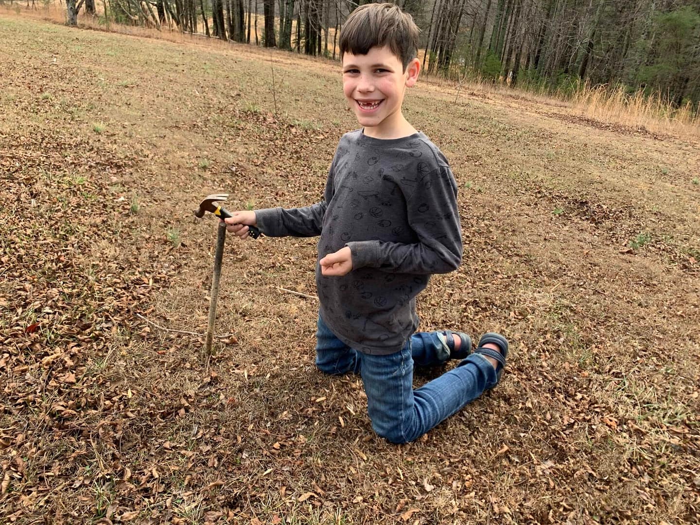 boy hammering a rebar into the grass