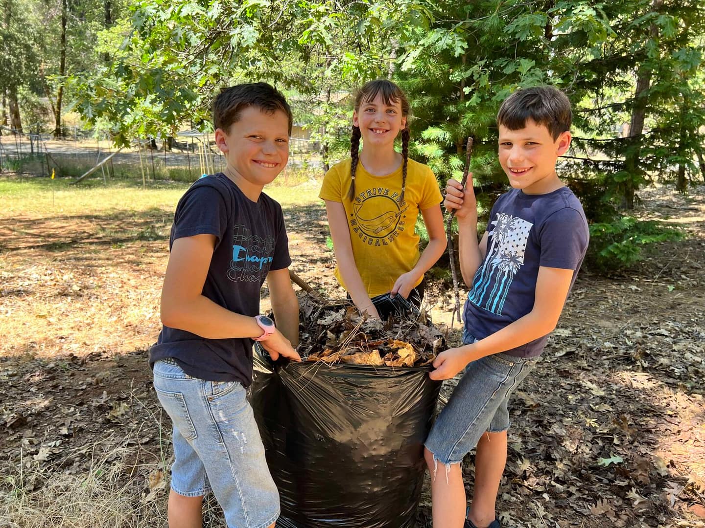 3 kids bagging leaves