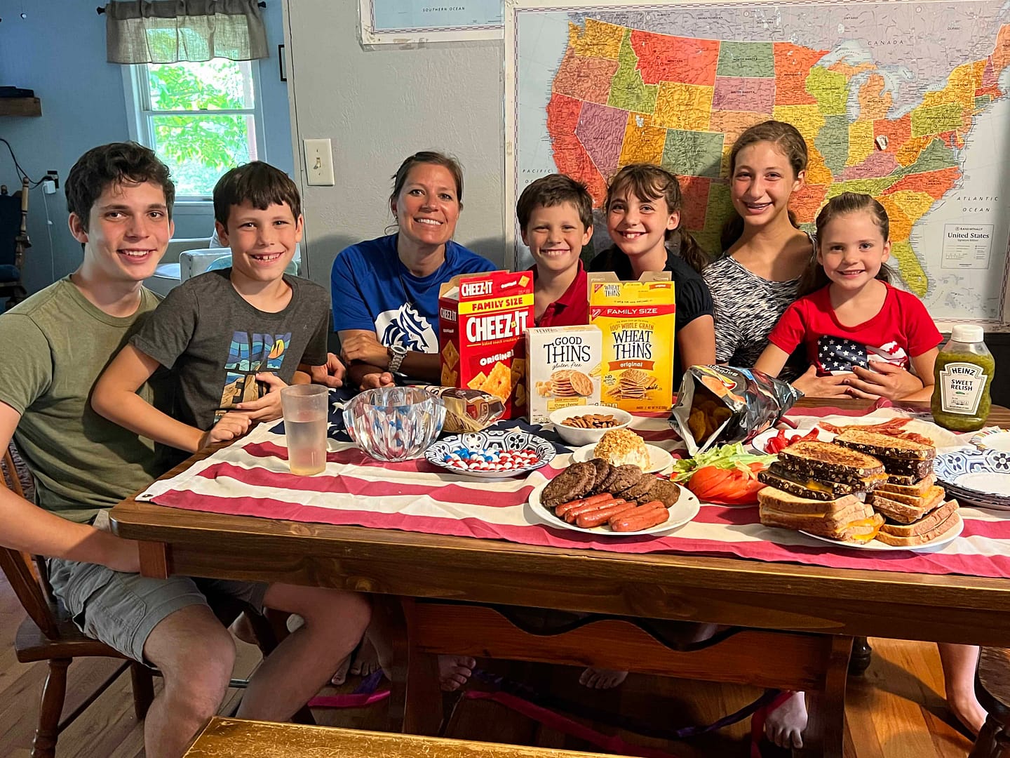 family sitting at a table with American flag and party foods for the Olympics