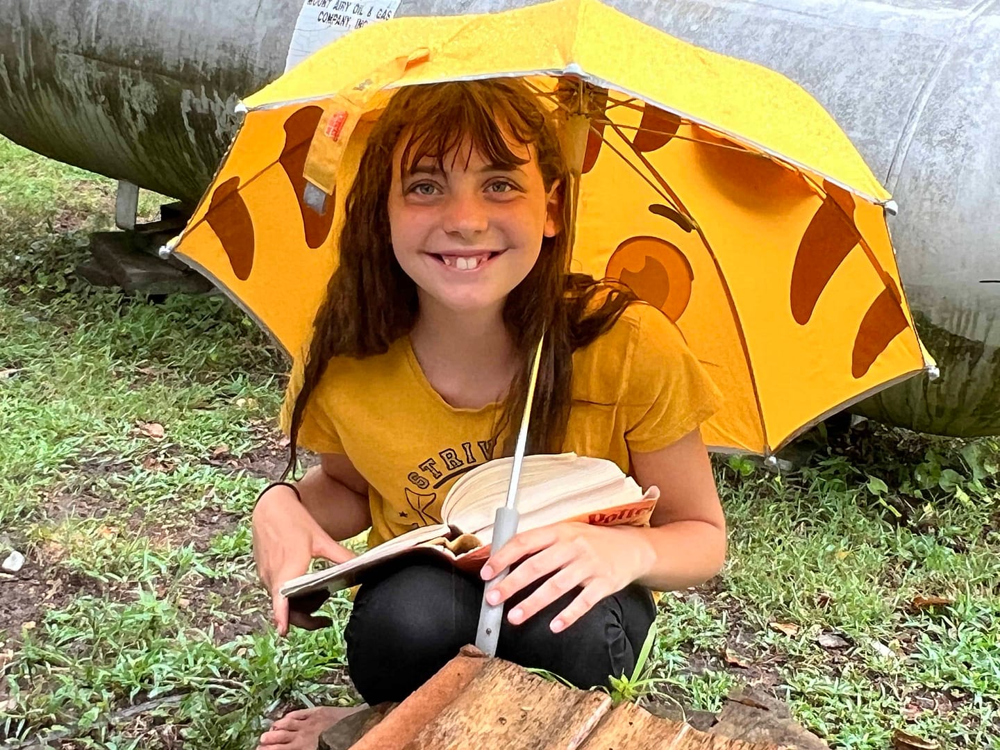 12 year old girl reading in the rain with an umbrella