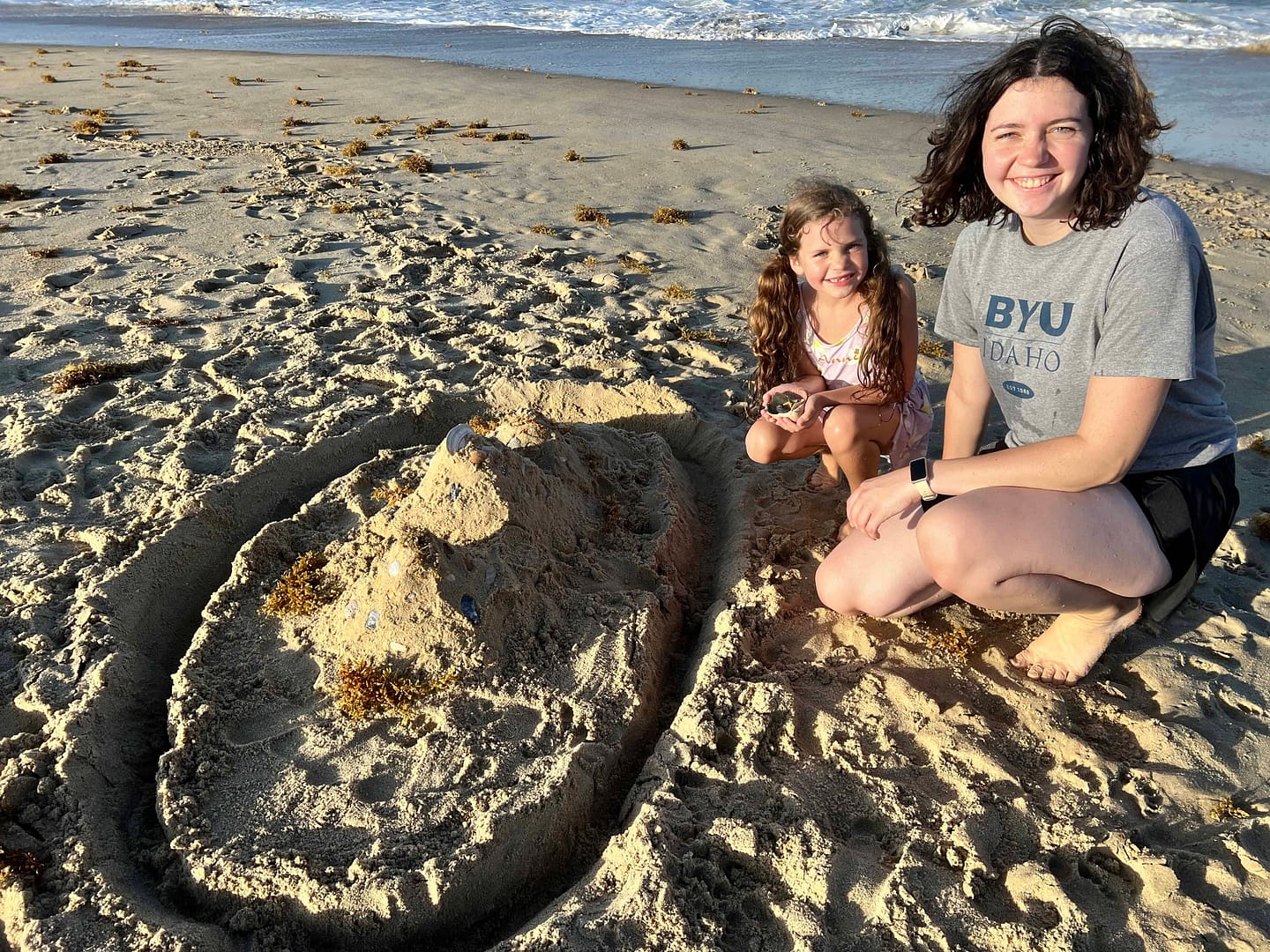 older sister and little sister posing with their sand castle