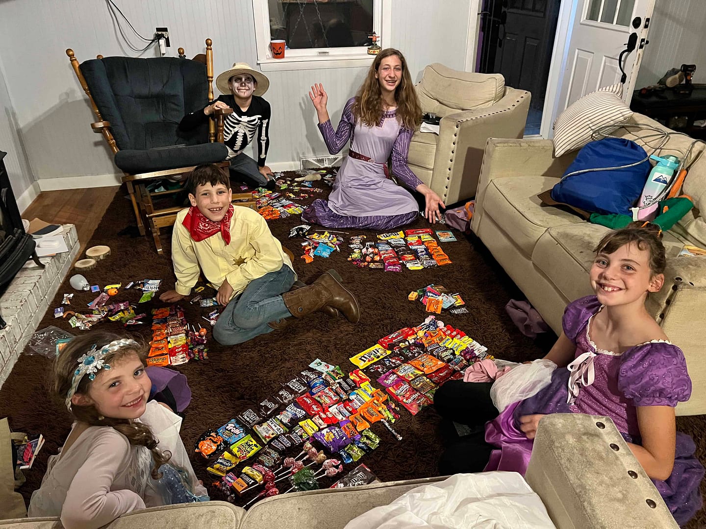 kids with their halloween candy spread on the living room floor