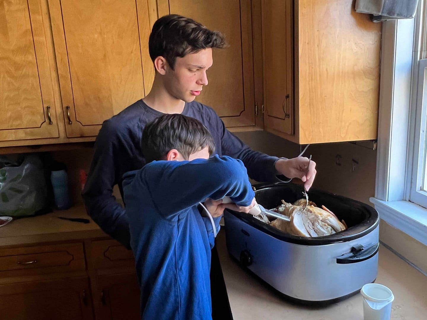 two boys cutting a Thanksgiving turkey