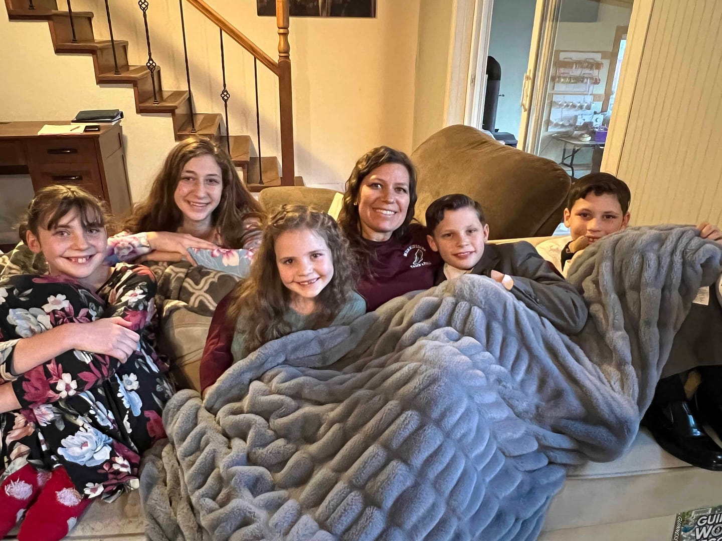 siblings snuggling with their aunt on the couch