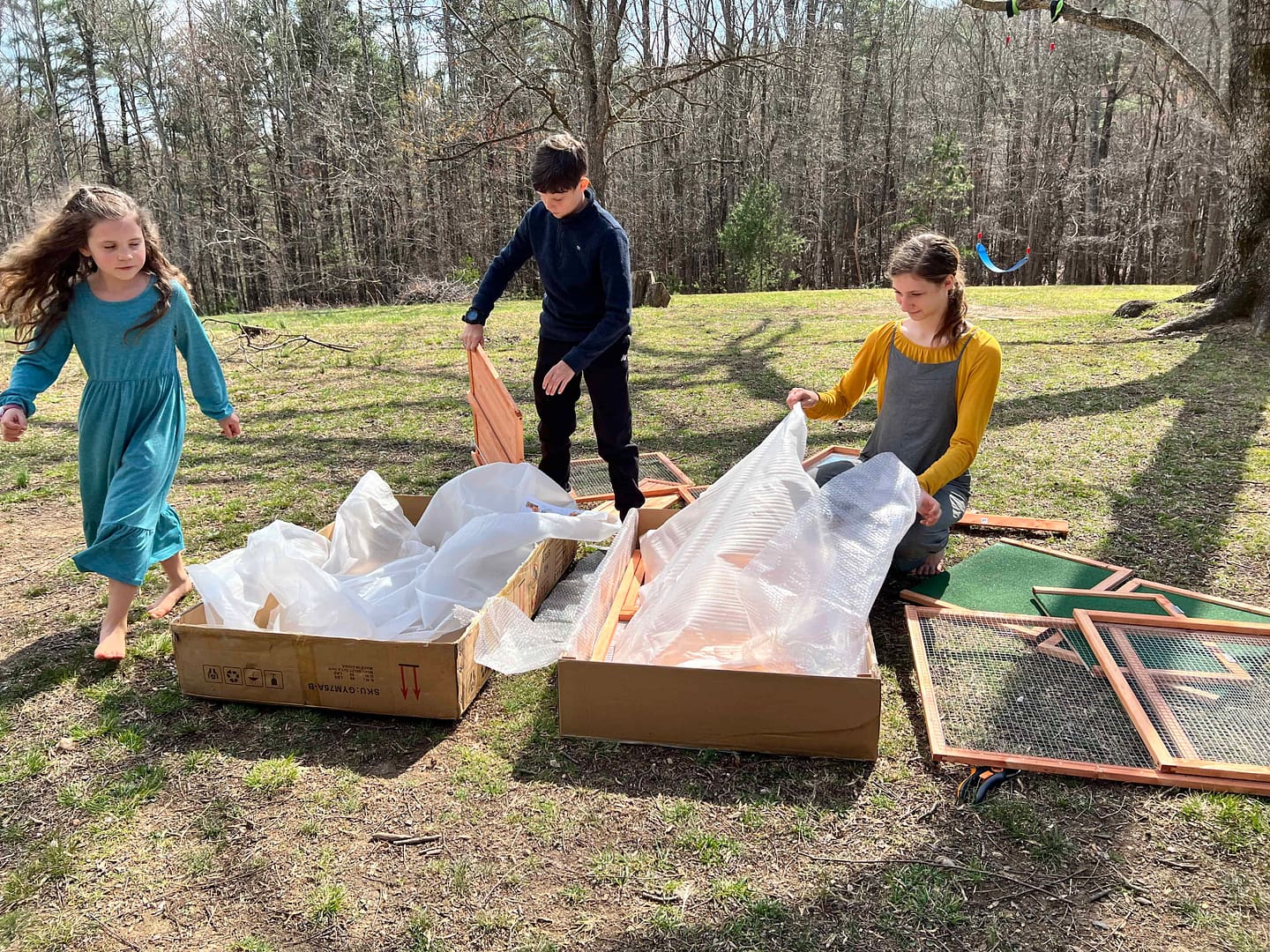 kids unpacking chicken coop parts to build it