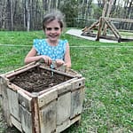 girl with wooden planter after planting seeds