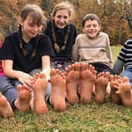 5 kids sitting barefoot next to each other in fall