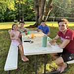 4 siblings eating at a picnic table