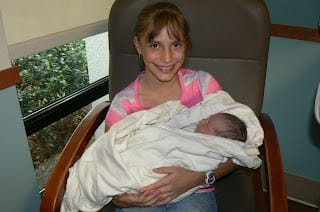 10 year old sister holding newborn baby brother in the hospital