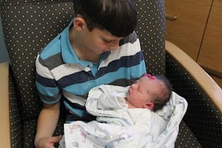 9 year old brother holding baby sister in the hospital