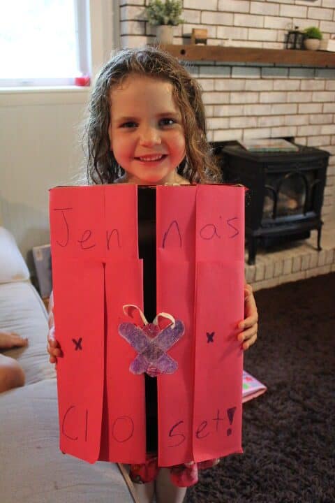girl holding a cardboard closet for her doll clothes