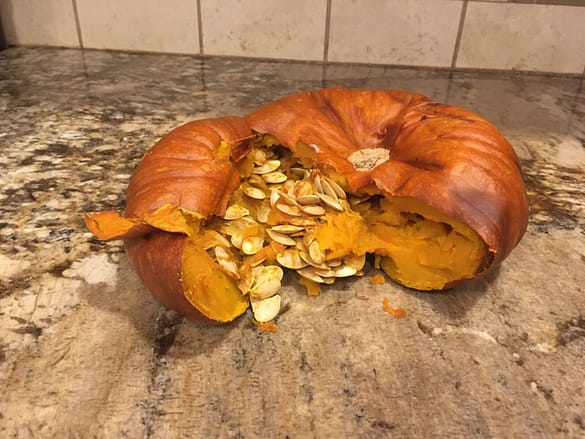A small orange pumpkin just out of the oven, all cooked.