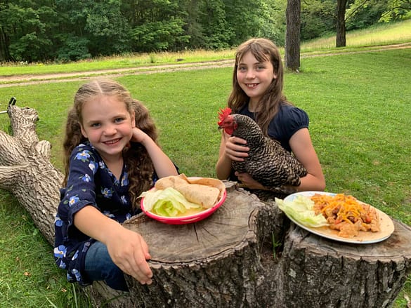 two girls eating fajitas on a stump
