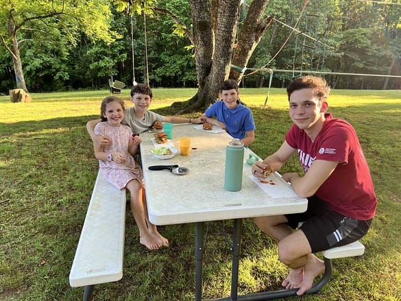 4 siblings eating at a picnic table