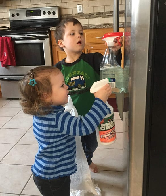 two kids cleaning the outside of the refrigerator