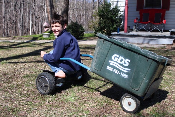 boy riding hoverboard with a cart picking up sticks
