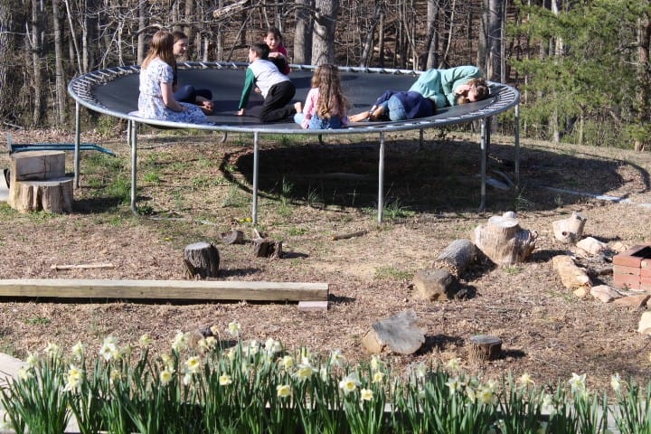 5 kids playing with the sister missionaries on a trampoline in early spring.