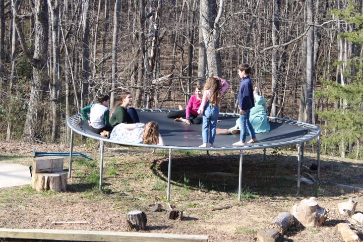 kids and sister missionaries playing on a trampoline
