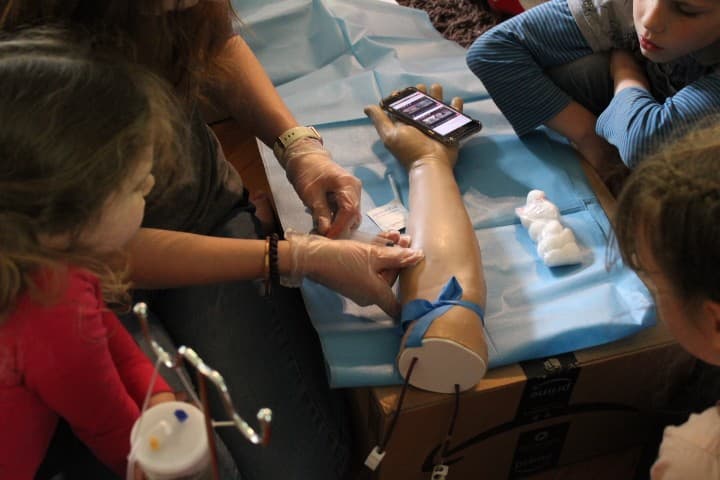 17 year old does a needle stick on a fake arm while little kids watch