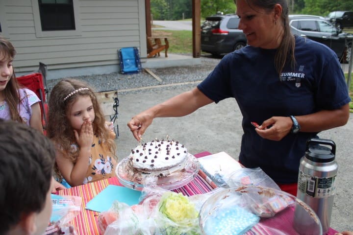 niece and aunt celebrating their birthday together with a cake at a camping trip